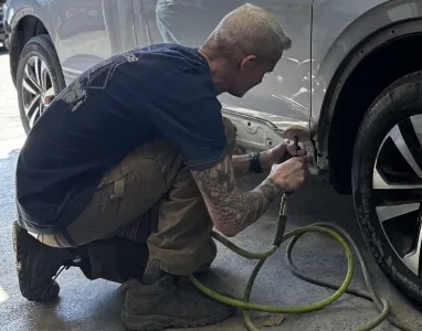 StormWise technician performing paintless dent repair on a silver SUV in Denver